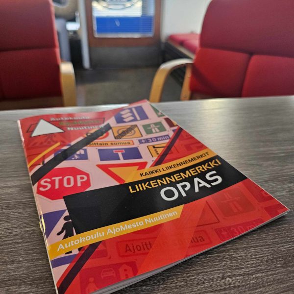 Liikennemerkkivihkonen käytössä – opiskelija selaa vihkosta autokoulun teoriatunnilla
