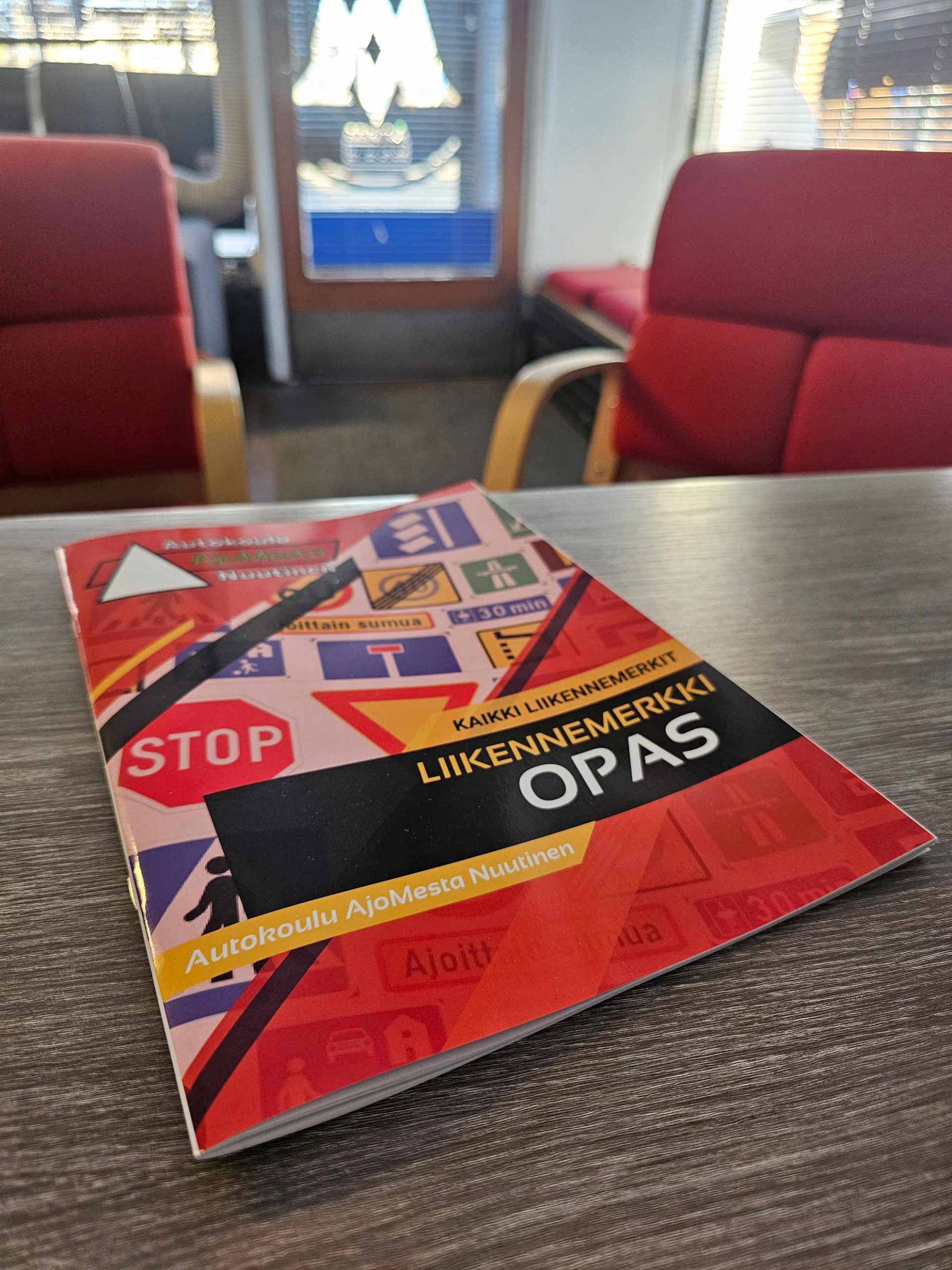 Liikennemerkkivihkonen käytössä – opiskelija selaa vihkosta autokoulun teoriatunnilla